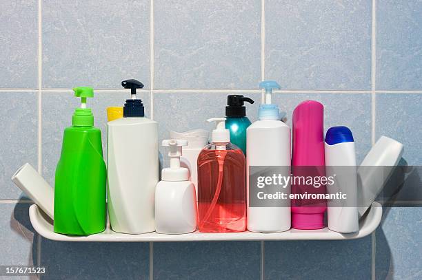 many shampoo and soap bottles on a bathroom or shower shelf.